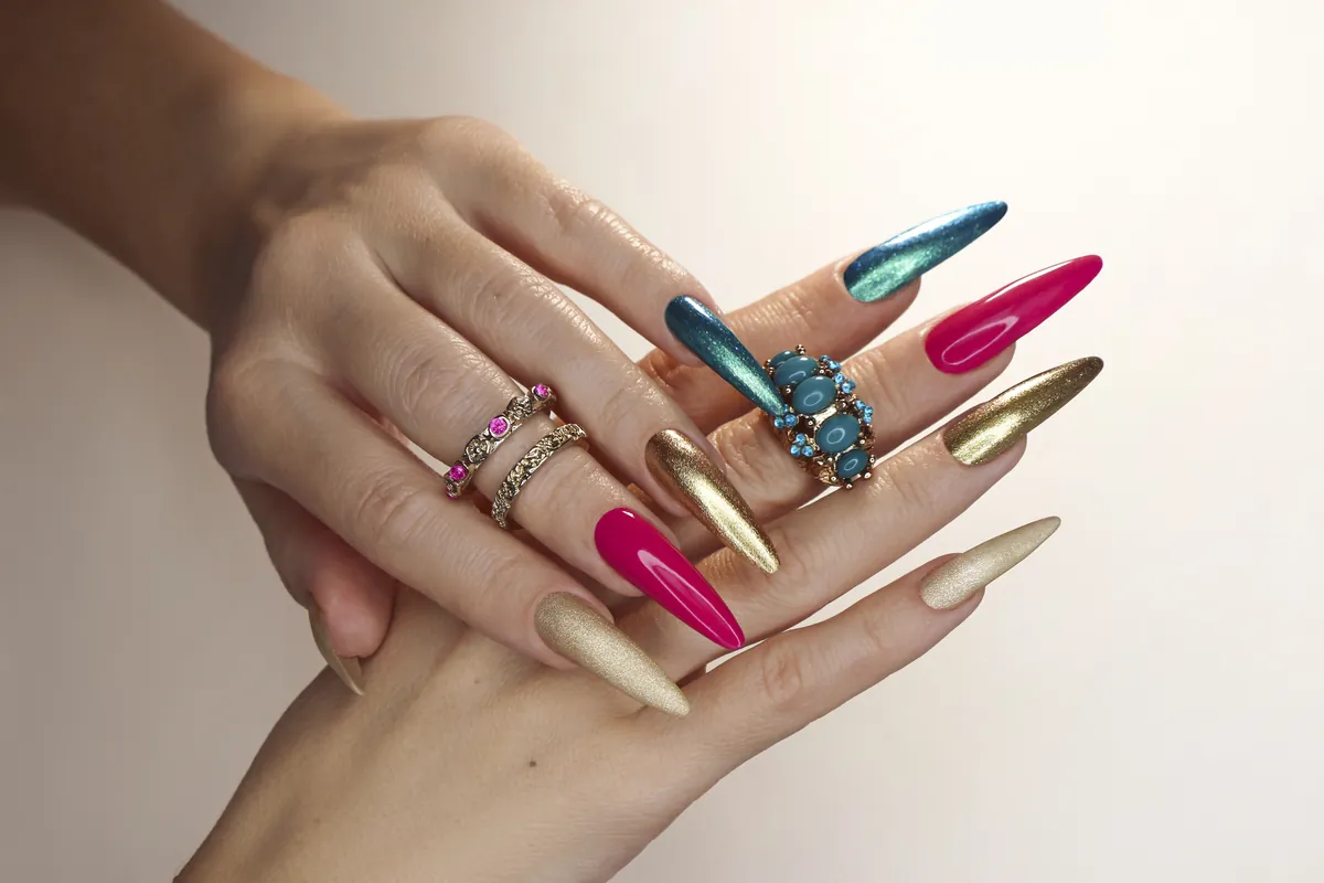 Long almond nails in gold, turquoise and pink worn with stacked rings