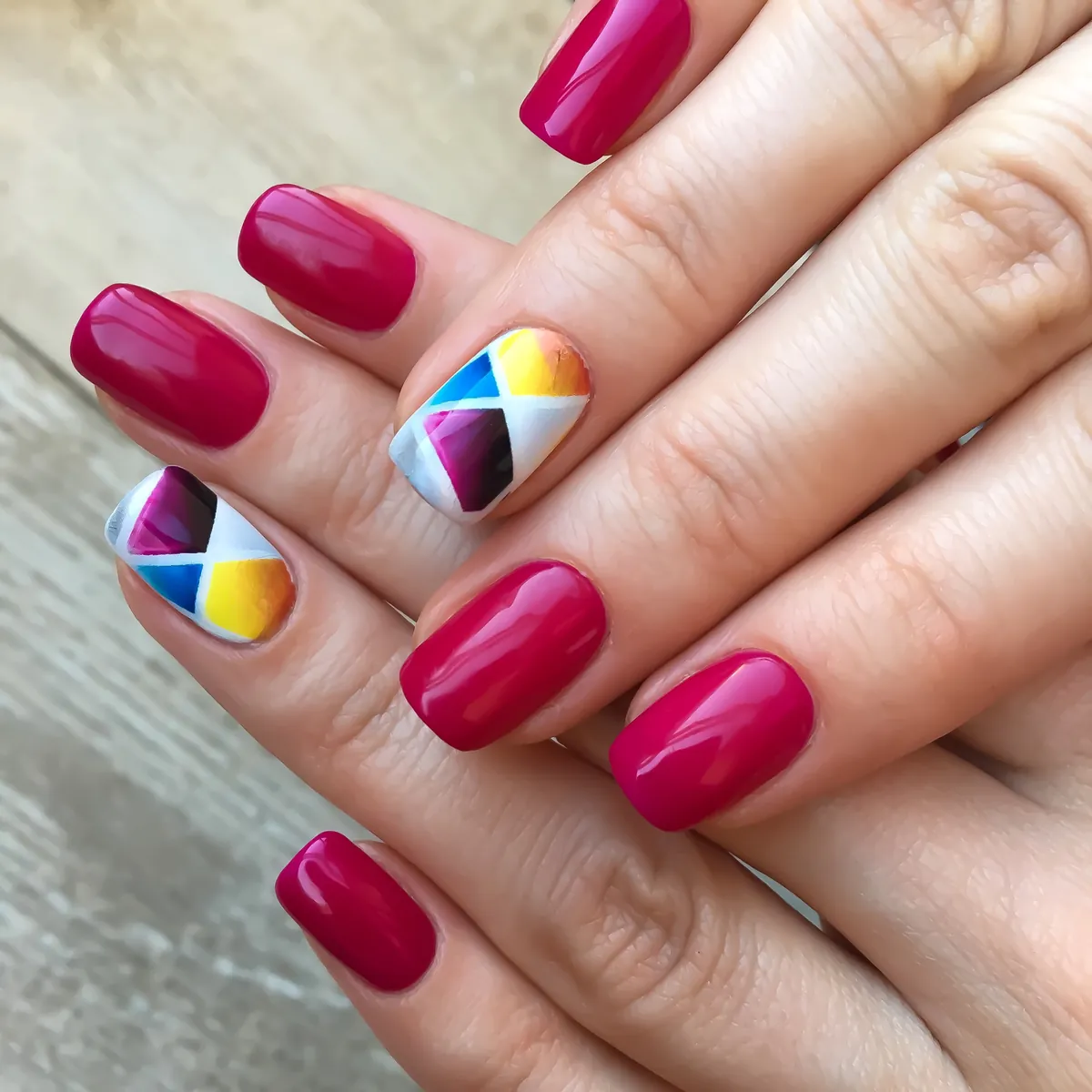 Raspberry nails with one accent nail in a bright geometric pattern