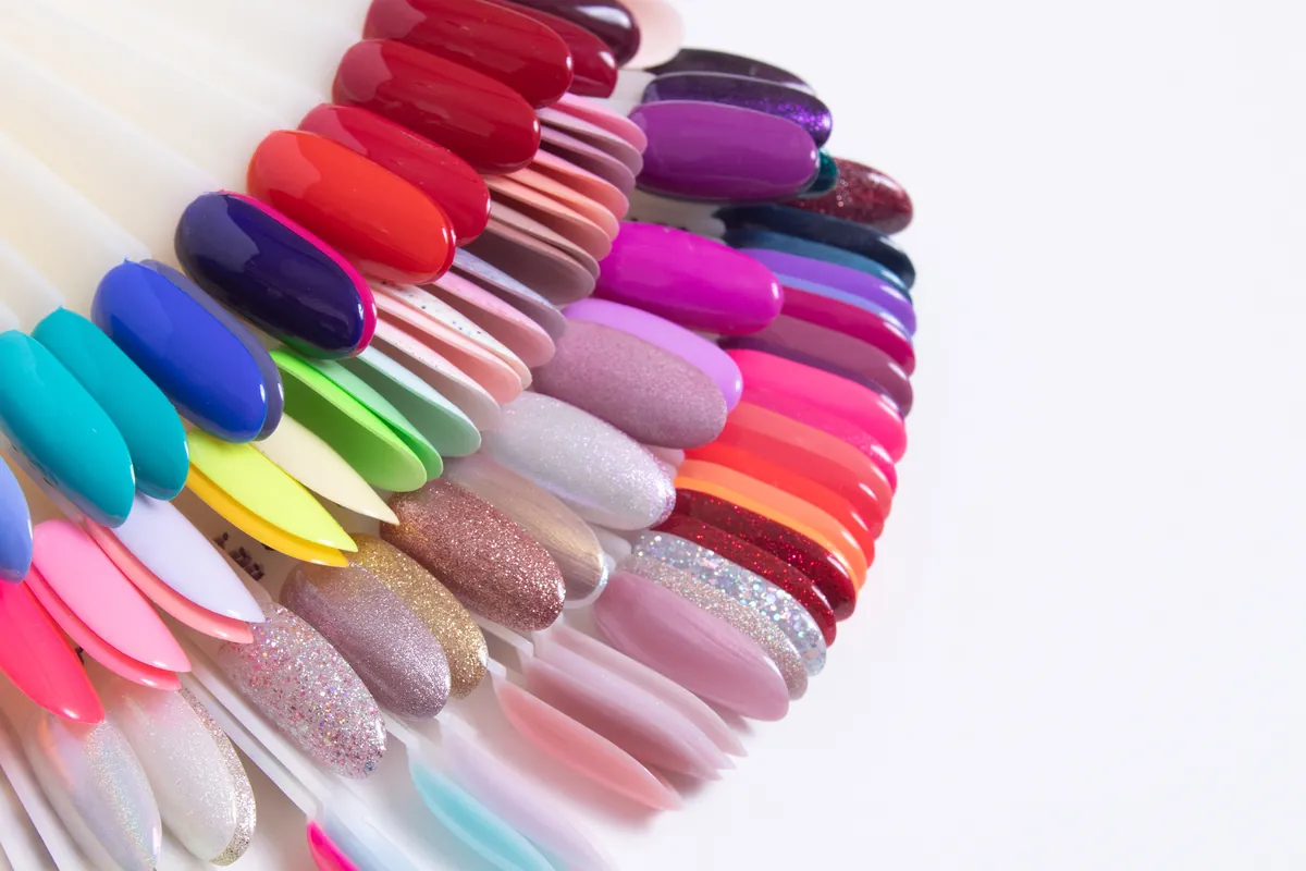 A fan of nail tips showing a rainbow palette of gel polish colours