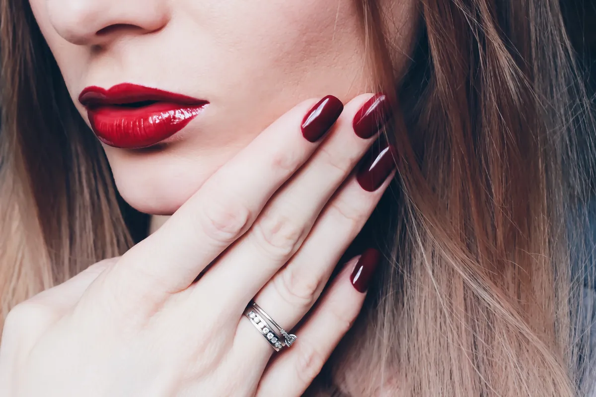 Close-up of red lips and a matching red manicure