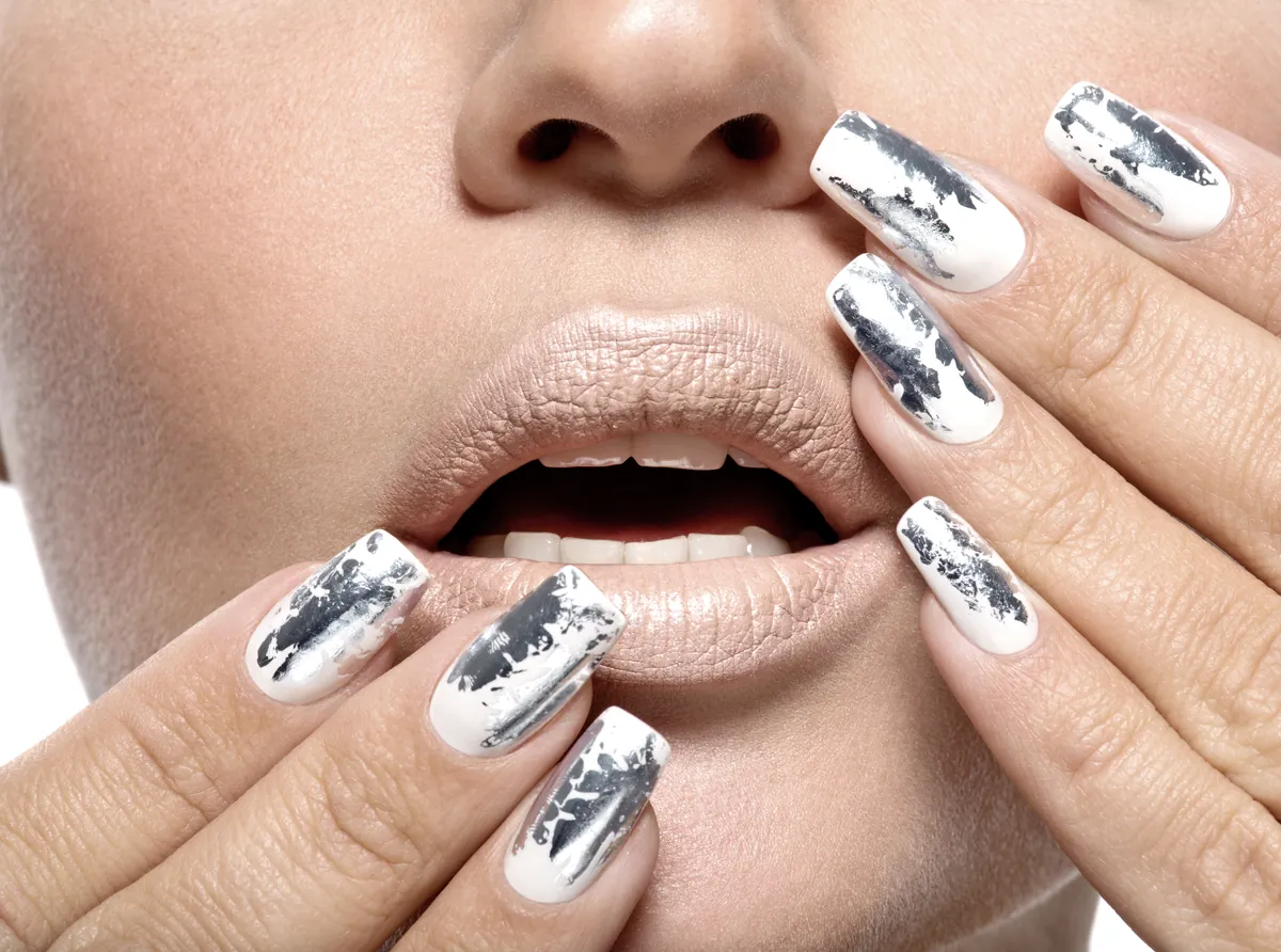 Nails with a mirror silver chrome finish held close to the lips